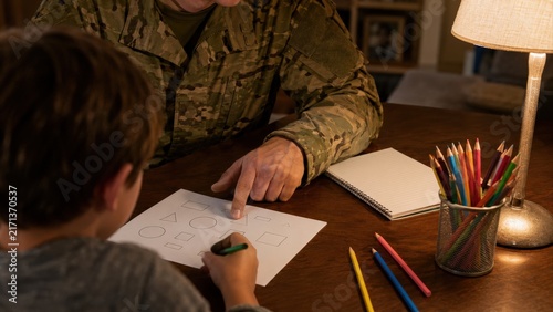 Soldier Helping Young Boy With Shape Worksheet at Home