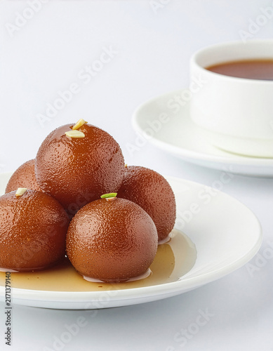 Stack Of Gulab Jamun Indian Dessert Balls Drizzled With Syrup Served With Tea On White Plate