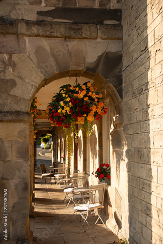 Obraz na plátne Cozy outdoor cafe terrace under ancient stone archway in historical British town