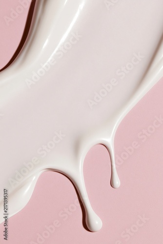 White cream smear and drip on pink background for cosmetic product ad