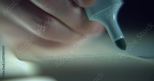 Extreme close-up footage of a man's hand highlighting lines of text with a blue highlighter, captured with a shallow depth of field and selective focus. Conceptual study and reading scene.
