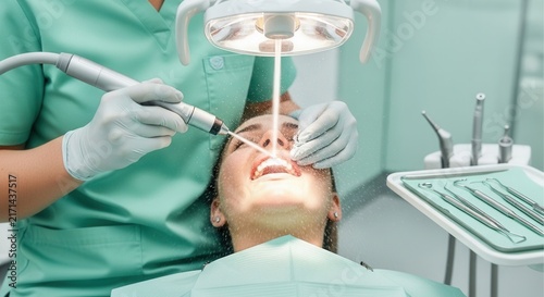 Dentist performing dental cleaning procedure with water spray and high-tech equipment on a patient in a modern clinic.