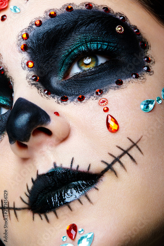 Halloween beauty close-up photography of female face. Beautiful woman adorned with Santa Muerte makeup.