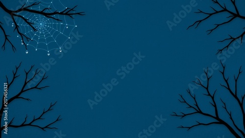 Spooky spider web on bare tree branches against a dark blue night sky background