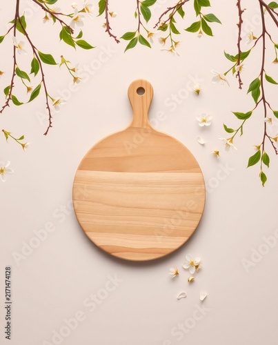 Rustic wooden cutting board with delicate spring blossoms overhead view