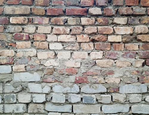 Fotografie An old weathered brick wall background featuring a combination of vintage red clay bricks and gray silicate bricks with rough concrete mortar joints in a rustic industrial style