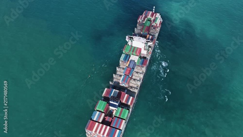 Shipping logistics. Commercial shipping. Cargo ship at sea, aerial top view. Freight container loaded on cargo tanker. Aerial cargo ship passing harbor. Cargo business. Container ship