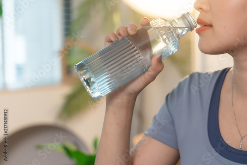 woman resting from excersise and drinking water from bottle.	