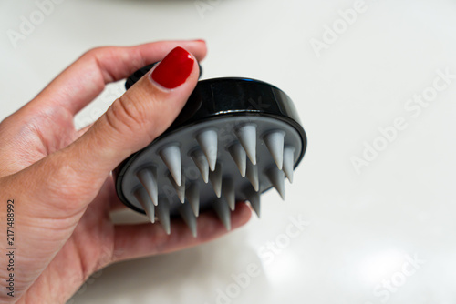 Close-up of a hand holding a silicone scalp massage brush, representing proactive scalp care and hair loss prevention. Gentle stimulation and cleansing support a healthy scalp routine