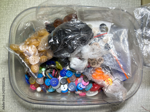 Obraz na plátně Assorted colorful sewing buttons in a clear plastic container