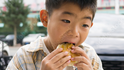 Принти на полотні Chinese kid eating local specialty Duijia, a traditional Chinese snack from Jingpeng Town, Hexigten Banner, Inner Mongolia