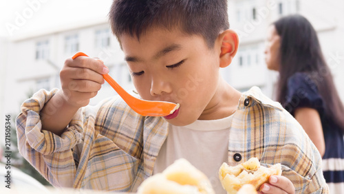 Принти на полотні Chinese kid eating local specialty Duijia, a traditional Chinese snack from Jingpeng Town, Hexigten Banner, Inner Mongolia