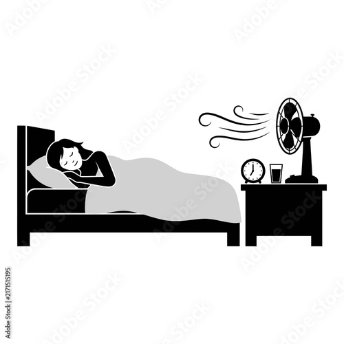 Silhouette of man sleeping in bed with electric fan blowing air