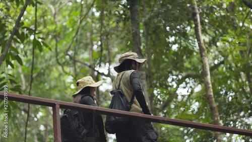 Photography Asian female hikers standing on wooden bridge walkway and enjoying scenic green forest
