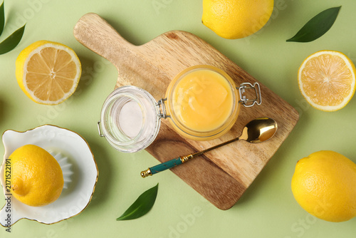Fotografie Jar of delicious lemon curd and squeezer on green background