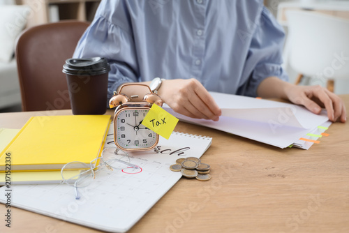 Foto Alarm clock with word TAX and businesswoman working on table in office