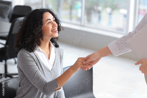 Female African-American job applicant with human resources manager shaking ha...