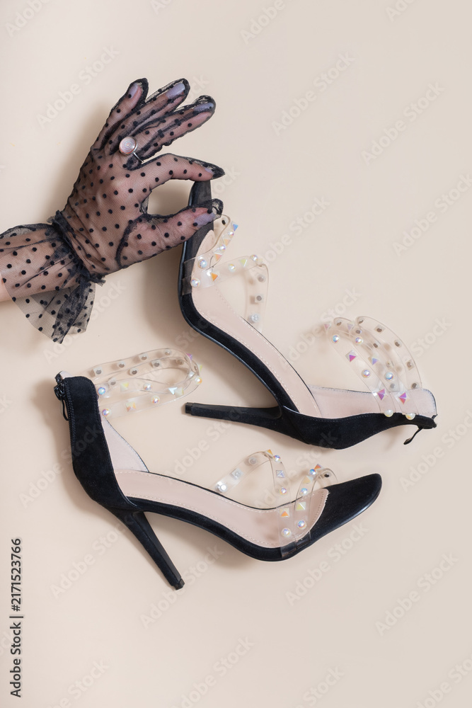 Naklejka premium High-heeled shoes with clear straps and decorative stones on light background