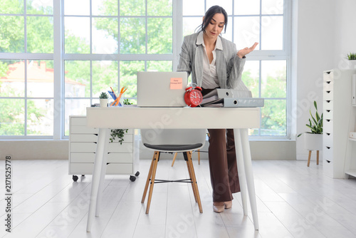 Stressed businesswoman at table in office. Time management concept