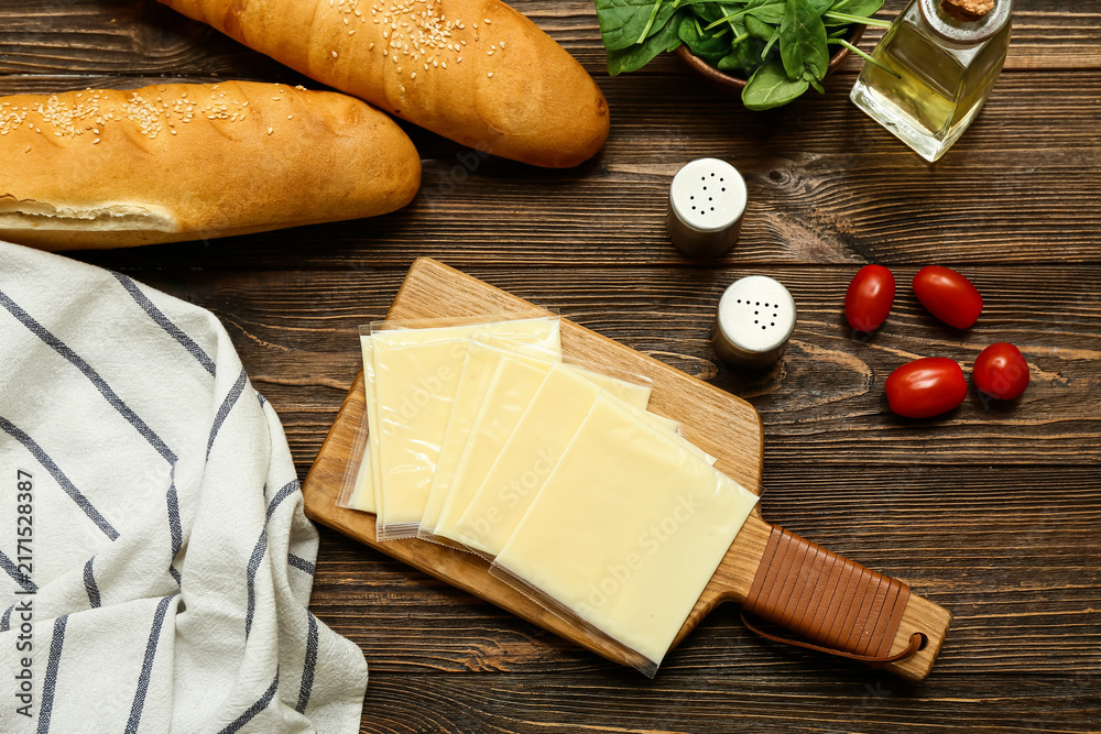 Naklejka premium Board with slices of delicious processed cheese, fresh tomatoes and bread on wooden table