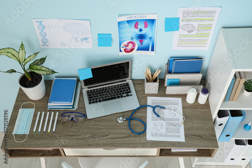 Medical students workplace with laptop and study materials near blue wall, to...