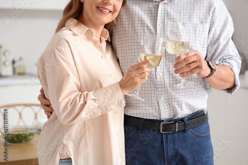 Mature couple with glasses of wine in kitchen