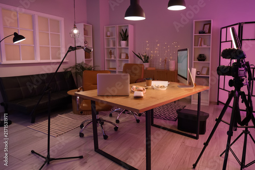 Podcasters workplace with laptop and headphones in studio at night