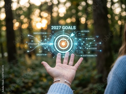 Hand reaching towards a glowing digital hologram of a target with 2027 goals, representing innovation, strategy, and future business success