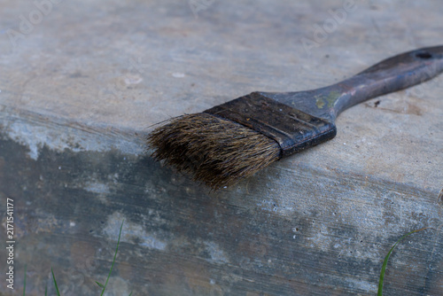 Fotografía Stock photo of an old used paintbrush with dried paint bristles resting on a weathered concrete step in a work environment