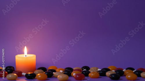 Candle flame pebble purple orange colorful seasonal scene glowing wax create warm scene, with polished glass decoration arranged against violet backdrop