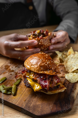 Person eating half of a cut double bacon cheeseburger