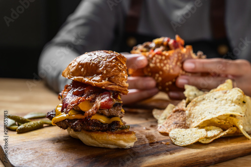 Person eating half of a cut double bacon cheeseburger