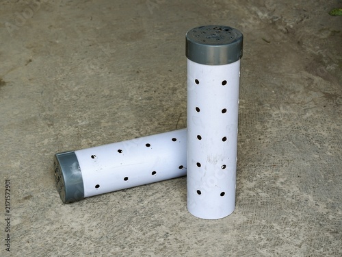 Two white perforated PVC biopore absorption pipes with grey end caps arranged on a concrete ground surface.