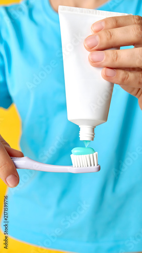 Hand Squeezing Toothpaste onto Toothbrush Colorful Background