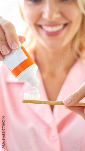 Woman Squeezing Toothpaste onto Bamboo Toothbrush Close Up