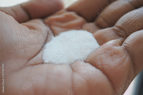 Foto Hand holding white sugar on palm