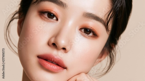 Close-up portrait of a young asian woman with radiant skin and warm-toned makeup