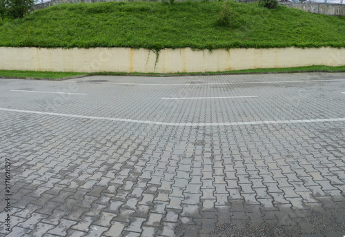 Empty paved road on a rainy day with a green grassy hill in the background.