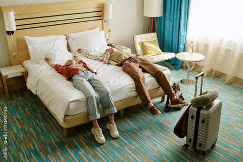 Foto Young adult Caucasian couple lying on bed in hotel room after arrival, high angle view