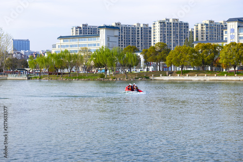 Red inflatable boat with passengers on an urban lake waterfront