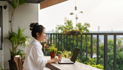Fototapeta 緑豊かなバルコニーでリラックスしながらPC作業をする若い女性