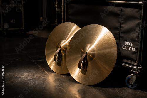 Polished orchestral cymbals leaning against padded cart backstage, music equipment and performance preparation concept
