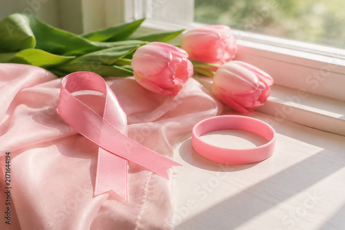 Pink ribbon, tulips and awareness wristband on window ledge, October Breast Cancer Awareness Month