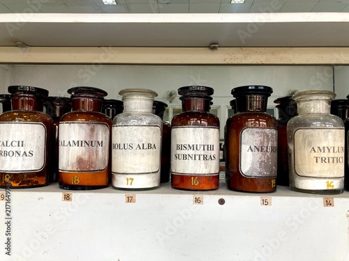 vintage apothecary glass bottles with latin chemical labels on shelf