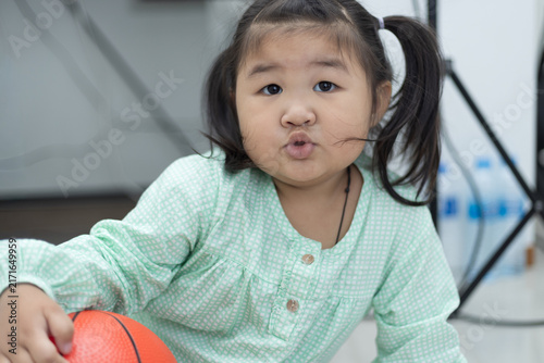 Фотография Asian Toddler Girl Pouting while Playing with Toy Basketball,A candid photograph