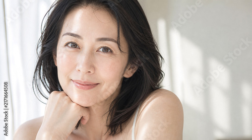 あごに手を添えて優しく微笑む上品な大人の女性のナチュラル美肌