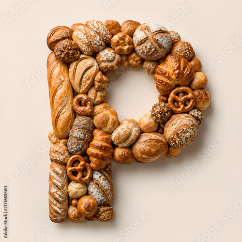 Creative letter P composed of assorted artisan breads, pastries, pretzels, and baked goods arranged on a light background.