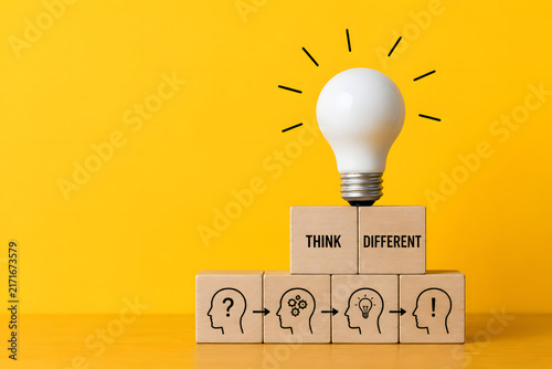 Light bulb and wooden blocks illustrate creative thinking, problem solving, innovation, and finding a different path toward new ideas.