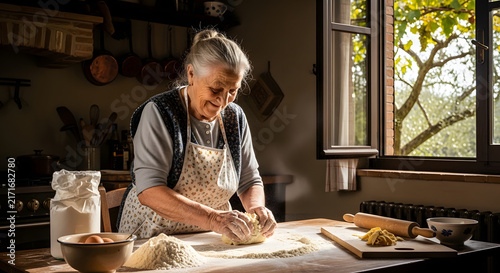 Elderly woman kneads fresh dough by hand in a sunlit rustic kitchen filled with baking supplies.