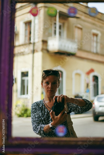 Foto Woman taking a self portrait with a camera in a mirror